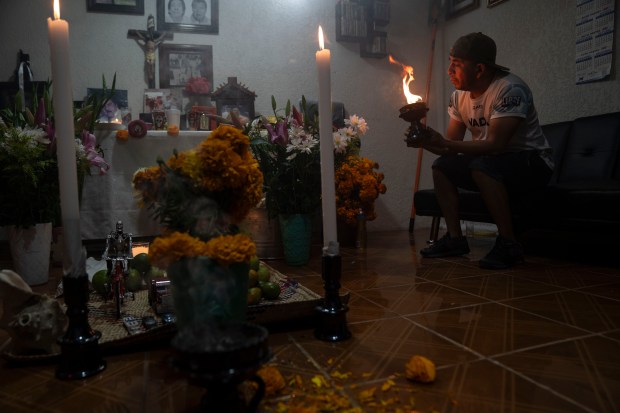 MEXICO CITY, MEXICO - NOVEMBER 1: A man lights incense next to a shrine to welcome back his family's ancestors and loved ones during 'Day of the Dead' celebrations on November 1, 2023 in Mexico City, Mexico. The Day of the Dead takes place every year on November 1 and 2. The celebration is one of the most colorful and popular in the country bringing millions of tourists to witness how people set offerings, decorate homes and cemeteries and organize family gatherings as a tribute to the dead. (Photo by Toya Sarno Jordan/Getty Images)