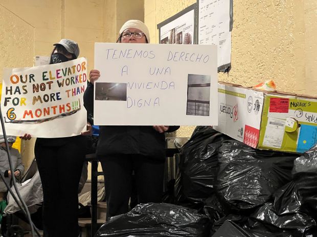 Residents stand amongst the garbage piled up inside in the lobby of 2201-05 Davidson Ave. in University Heights. Residents filed a suit against their landlord today over poor conditions. (Téa Kvetenadze)