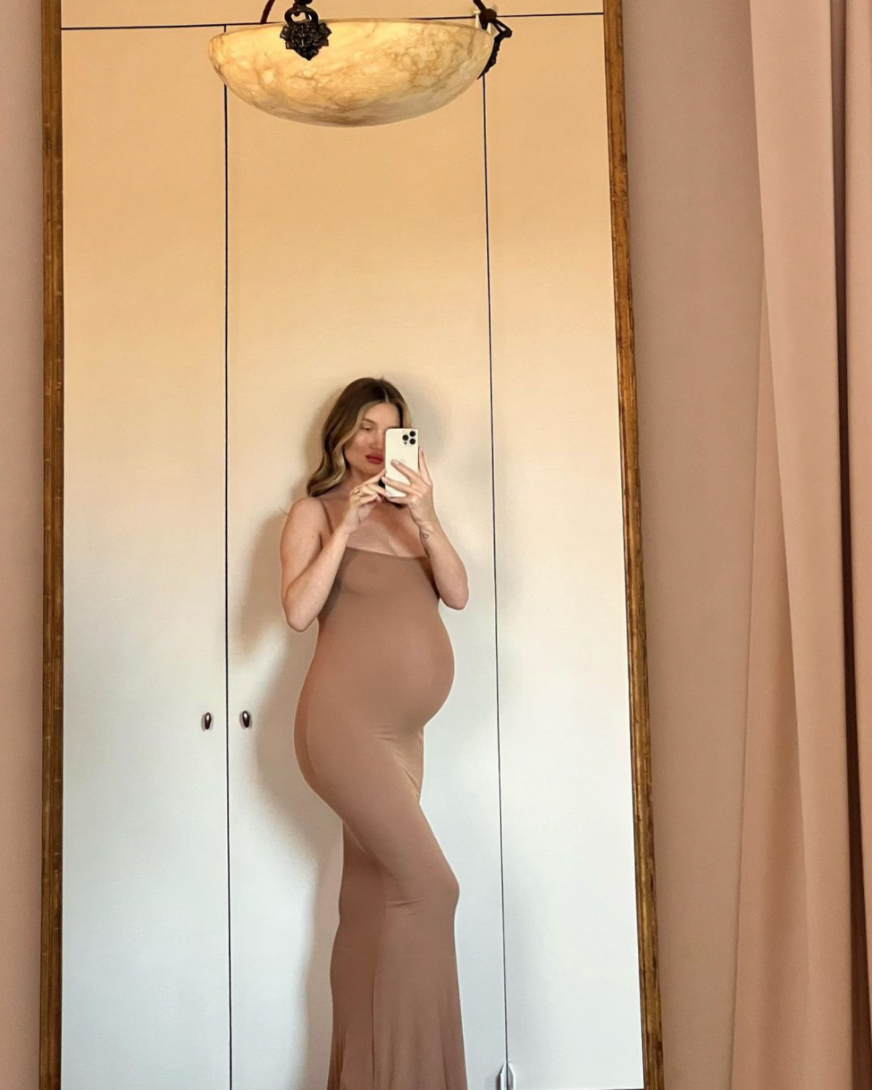 Model Rosie Huntington-Whiteley, 34, shows off her growing baby bump with a curve-hugging dress on Sunday, Jan. 23, 2022. The model is expecting her second child with fiancé Jason Statham.