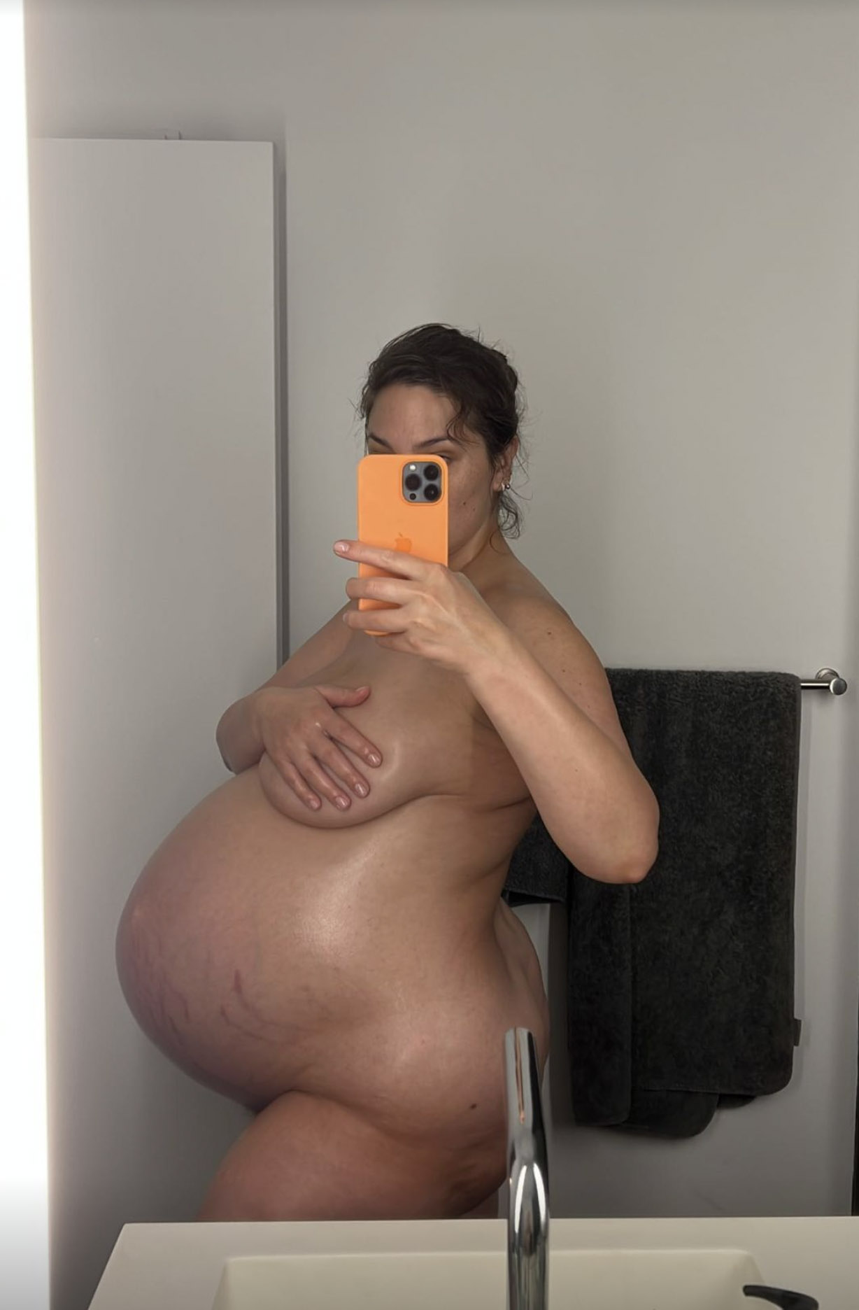 Ashley Graham strips down to show off her growing baby bump as she gets ready to give birth to twin boys with husband Justin Ervin on Monday, Dec. 20, 2021.